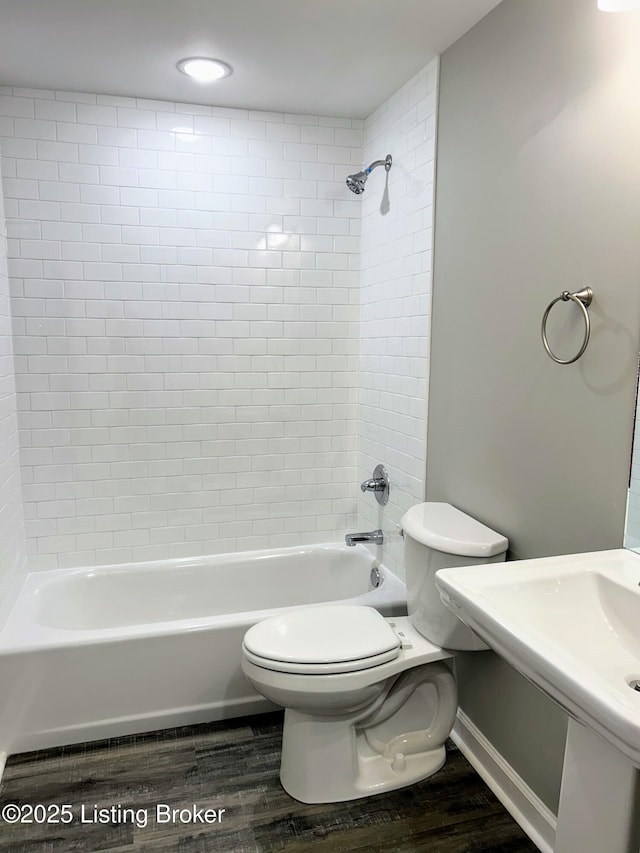 bathroom with tiled shower / bath, wood-type flooring, and toilet