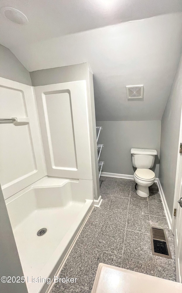 bathroom with vaulted ceiling, a shower, and toilet