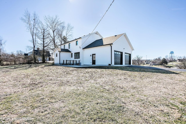 rear view of property with a garage and a lawn