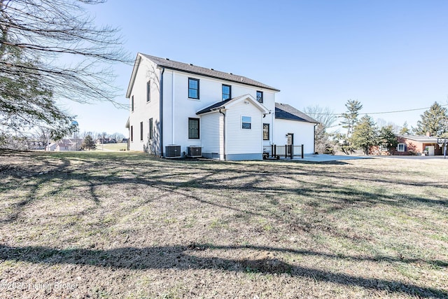 rear view of property featuring a yard, central AC unit, and a patio area