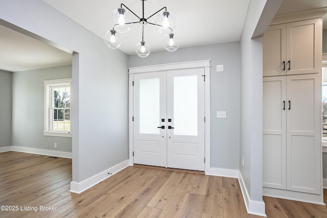 foyer entrance featuring french doors, a chandelier, and light hardwood / wood-style flooring