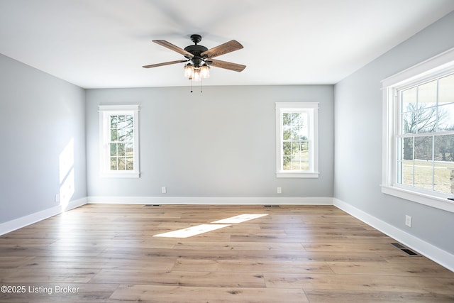 spare room featuring a wealth of natural light, ceiling fan, and light wood-type flooring