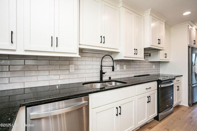 kitchen featuring white cabinetry, sink, backsplash, dark stone counters, and stainless steel appliances