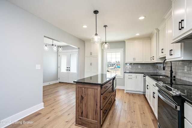 kitchen with range with electric stovetop, a kitchen island, pendant lighting, white cabinetry, and decorative backsplash