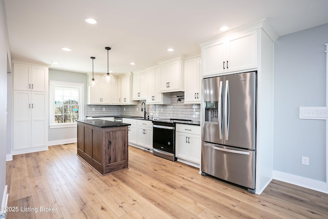 kitchen featuring pendant lighting, sink, appliances with stainless steel finishes, white cabinetry, and tasteful backsplash