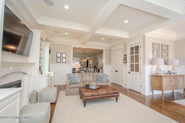 living room with coffered ceiling, crown molding, wood-type flooring, a brick fireplace, and beam ceiling