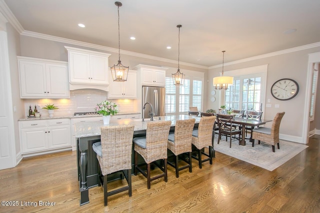 kitchen with light stone countertops, a kitchen island with sink, light hardwood / wood-style flooring, and white cabinets