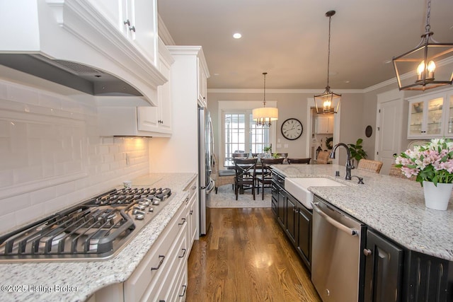 kitchen featuring sink, appliances with stainless steel finishes, white cabinetry, light stone countertops, and custom range hood