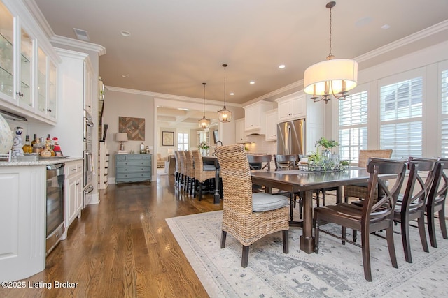 dining area featuring dark wood-type flooring, ornamental molding, beverage cooler, and bar area