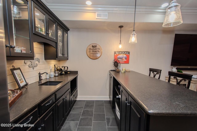 kitchen featuring pendant lighting, sink, dark tile patterned flooring, a kitchen bar, and ornamental molding