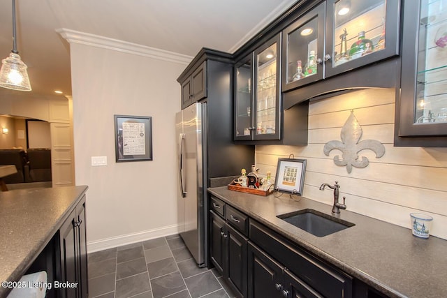 kitchen featuring sink, stainless steel fridge, hanging light fixtures, ornamental molding, and dark tile patterned floors