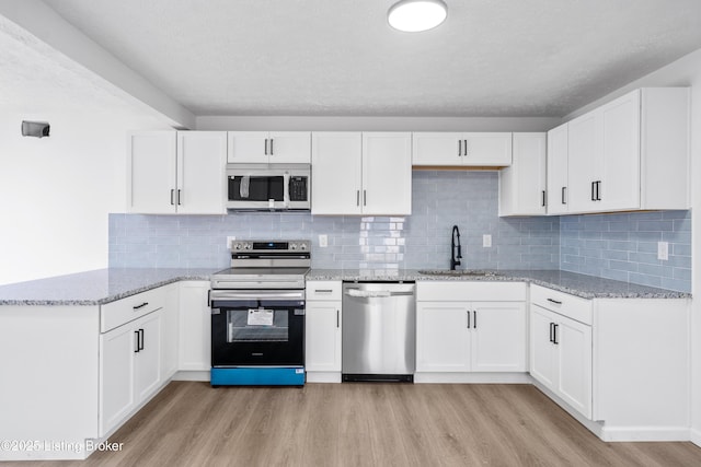 kitchen featuring stainless steel appliances, white cabinetry, sink, and light hardwood / wood-style floors