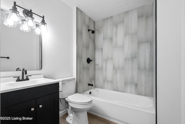 full bathroom featuring hardwood / wood-style flooring, tiled shower / bath combo, vanity, a textured ceiling, and toilet