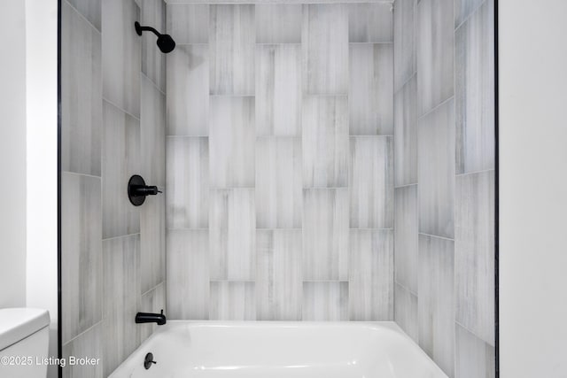 bathroom with tiled shower / bath combo and toilet