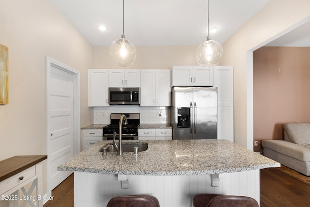 kitchen with white cabinetry, hanging light fixtures, a breakfast bar area, and stainless steel appliances