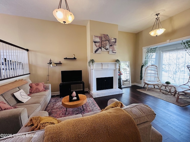 living room featuring a brick fireplace and dark hardwood / wood-style flooring