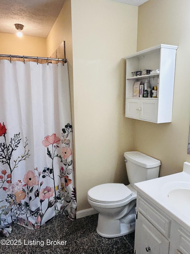 bathroom featuring walk in shower, vanity, toilet, and a textured ceiling