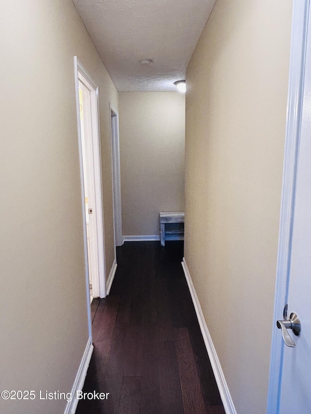 hallway featuring dark wood-type flooring and a textured ceiling