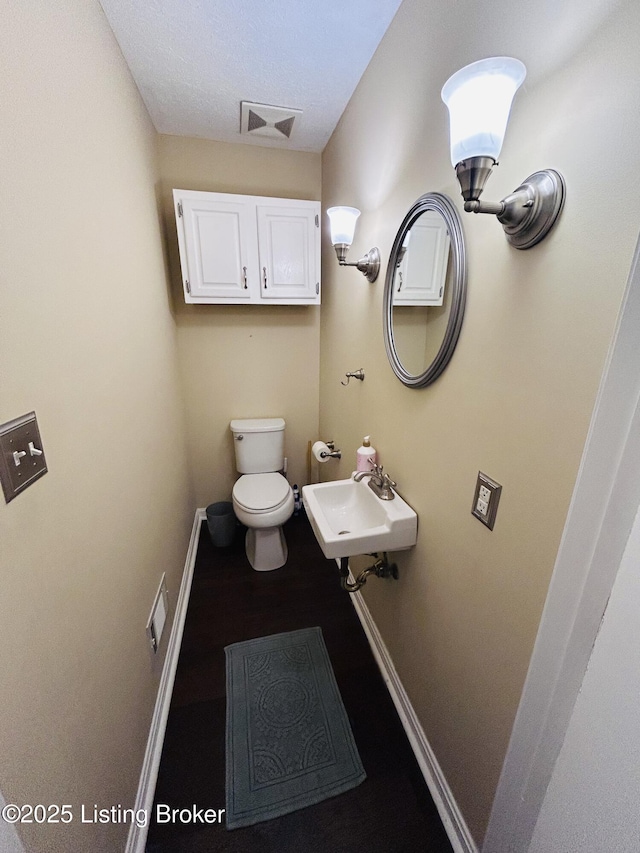 bathroom featuring sink, a textured ceiling, and toilet