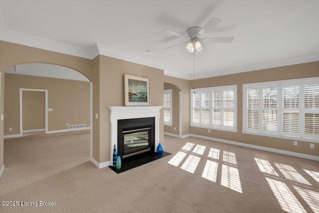 unfurnished living room featuring visible vents, ornamental molding, a fireplace with flush hearth, ceiling fan, and baseboards