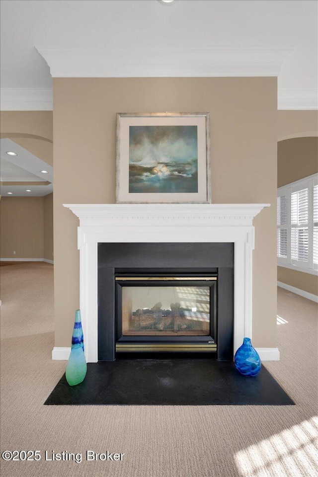 interior details with a fireplace with flush hearth, carpet, crown molding, and baseboards