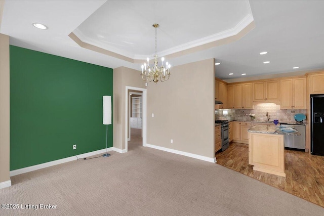 kitchen with a sink, black fridge with ice dispenser, stainless steel gas stove, light brown cabinetry, and a raised ceiling