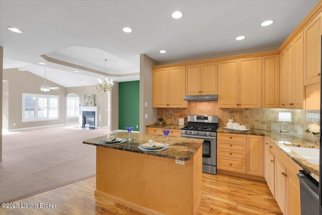 kitchen with a center island, a fireplace, stainless steel appliances, light brown cabinetry, and under cabinet range hood