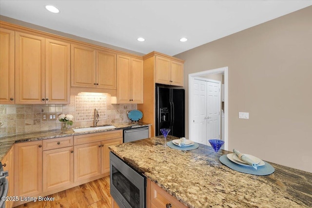 kitchen featuring a sink, stainless steel appliances, light brown cabinetry, light wood-type flooring, and backsplash