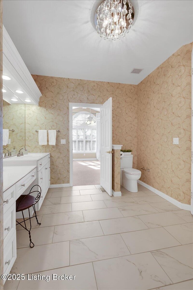 bathroom featuring toilet, wallpapered walls, baseboards, and marble finish floor