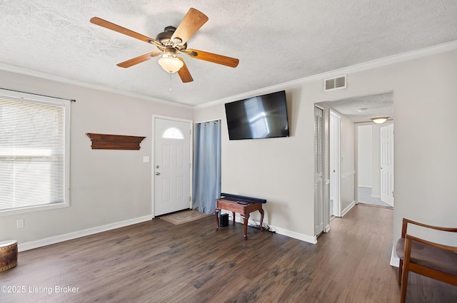 foyer featuring dark wood-type flooring, ceiling fan, crown molding, and a textured ceiling