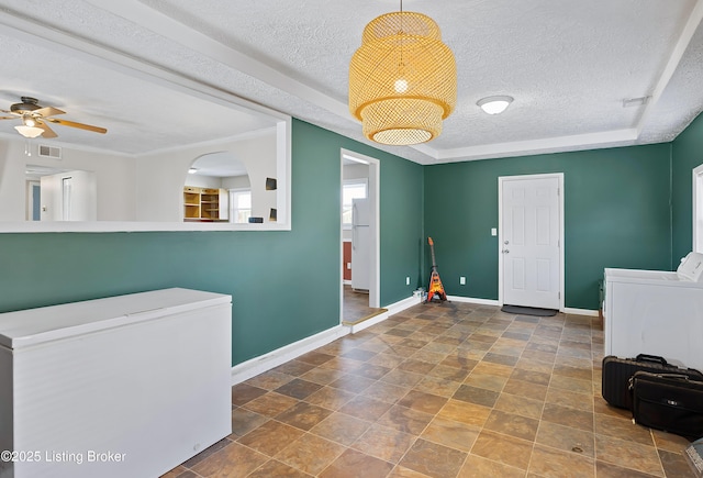 entryway with ceiling fan, washer and dryer, and a textured ceiling