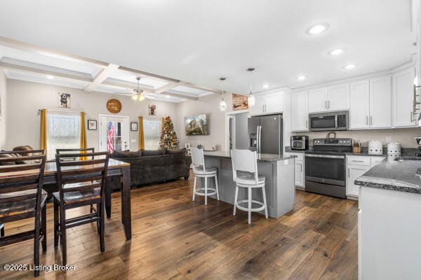 kitchen with appliances with stainless steel finishes, coffered ceiling, white cabinets, dark hardwood / wood-style flooring, and beamed ceiling