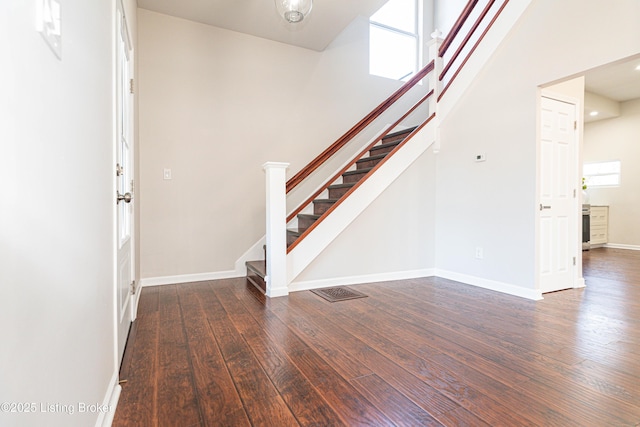 entryway with dark hardwood / wood-style flooring and a towering ceiling