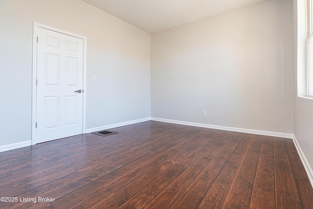 empty room with dark hardwood / wood-style floors and a textured ceiling