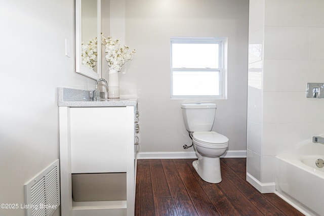 bathroom with vanity, hardwood / wood-style floors, a tub, and toilet