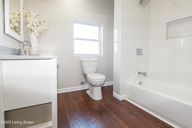 full bathroom with vanity, tiled shower / bath, hardwood / wood-style floors, and toilet