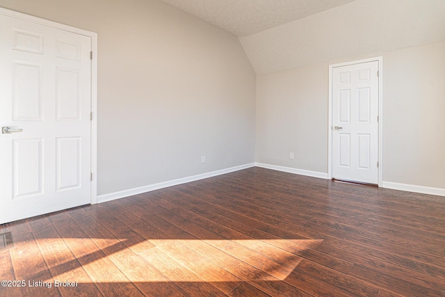 spare room with vaulted ceiling and dark hardwood / wood-style floors