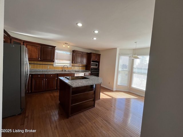 kitchen featuring dark wood-type flooring, dark brown cabinetry, appliances with stainless steel finishes, and a center island