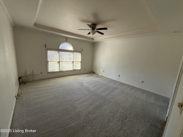 empty room featuring ornamental molding, carpet floors, ceiling fan, and a tray ceiling