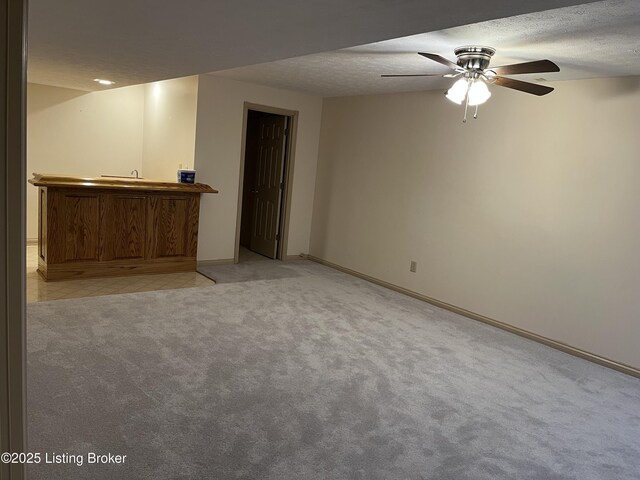 carpeted spare room featuring bar, ceiling fan, and a textured ceiling