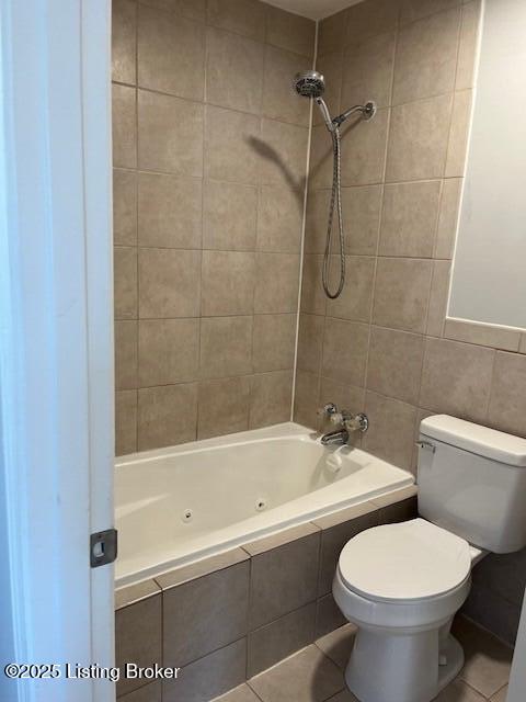 bathroom featuring tiled shower / bath, tile walls, tile patterned floors, and toilet