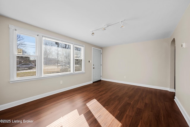 empty room featuring dark hardwood / wood-style floors and track lighting