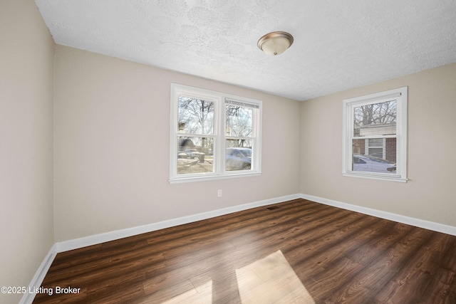 unfurnished room featuring dark hardwood / wood-style floors, a textured ceiling, and a wealth of natural light