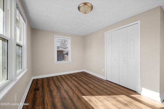 unfurnished bedroom with hardwood / wood-style flooring, a closet, and a textured ceiling