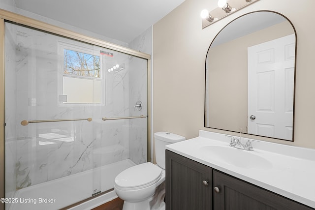 bathroom featuring vanity, a shower with shower door, and toilet