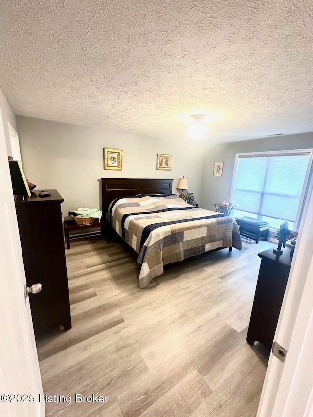 bedroom with light hardwood / wood-style flooring and a textured ceiling