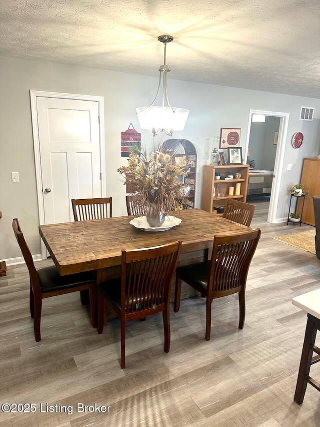 dining space with a textured ceiling and light wood-type flooring