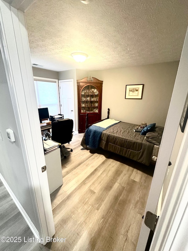 bedroom featuring hardwood / wood-style flooring and a textured ceiling