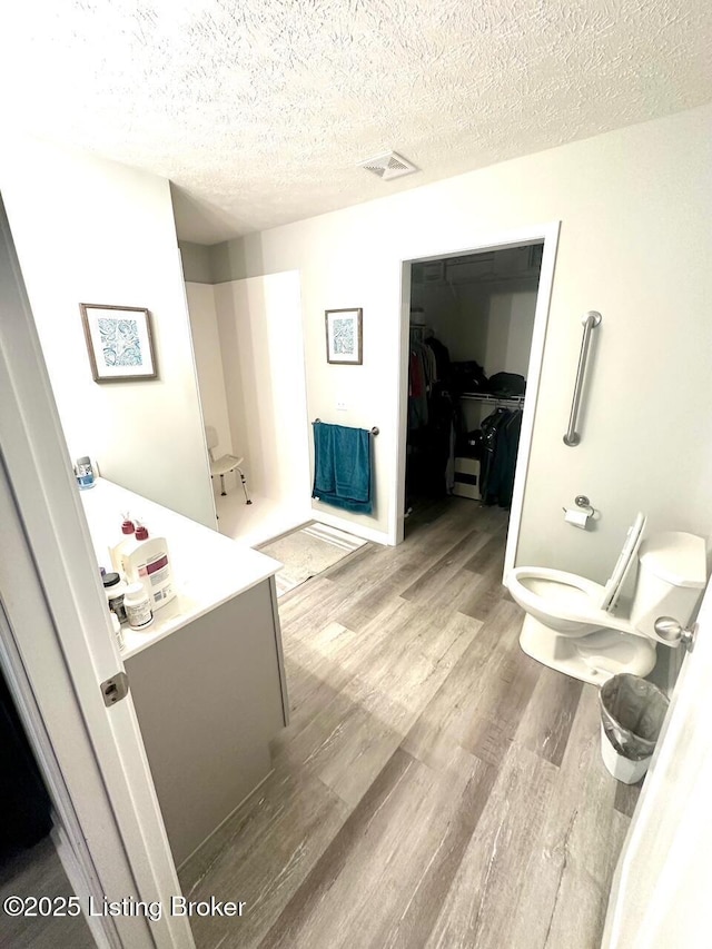 bathroom featuring vanity, hardwood / wood-style floors, a textured ceiling, and toilet