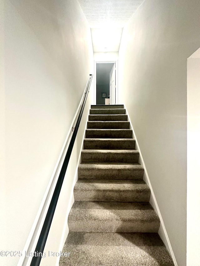 stairs featuring carpet and a textured ceiling